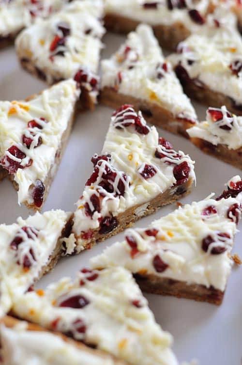 Top view of white chocolate drizzled cranberry bliss bars cut into triangle shapes.