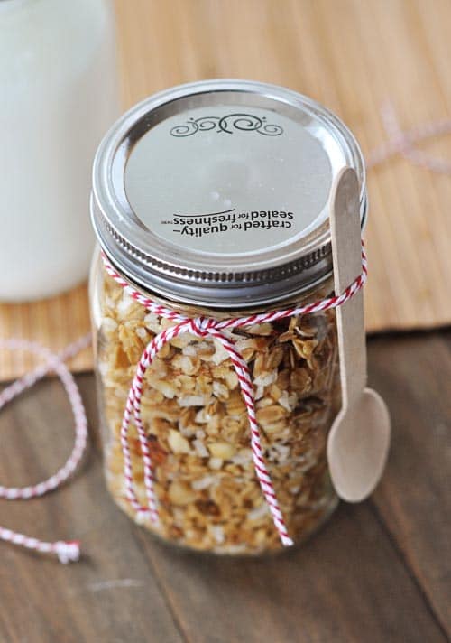 Mason jar full of homemade coconut granola with a spoon tied on the jar with a ribbon.
