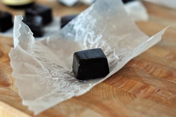 An unwrapped licorice caramel with other caramels in the background.