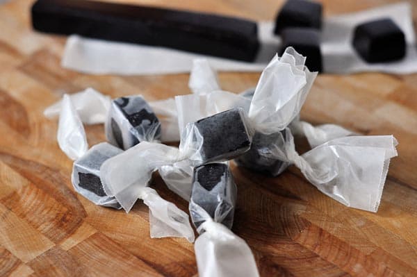 Wrapped licorice caramels on a wooden counter.