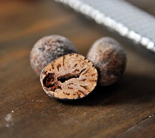 Three balls of nutmeg with the front one split in half.