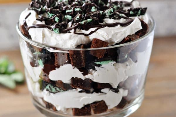 Side view of a trifle dish with layered brownies, whipped cream, and mint Oreo's.