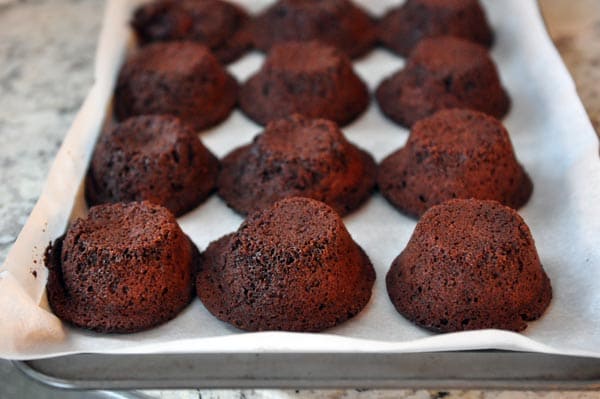 twelve mini chocolate cakes on a cookie sheet