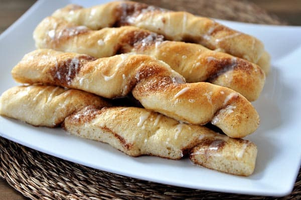 White platter with stacked cinnamon and sugar breadsticks.