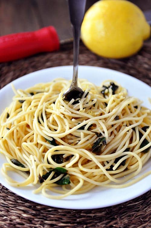 Top view of a plate full of cooked spaghetti with a fork in the middle.