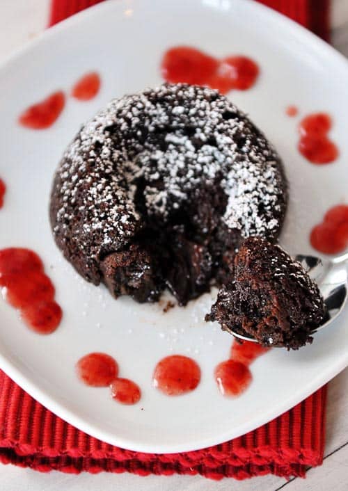 Top view of a chocolate molten cake sprinkled with powdered sugar on a white plate.