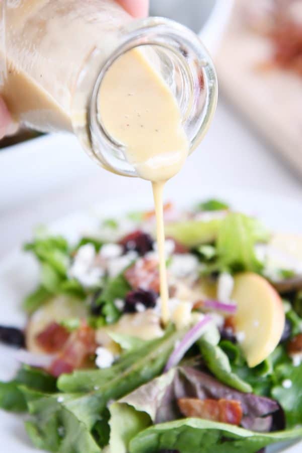 pouring vinaigrette over amazing spinach salad