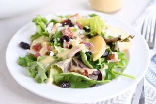 dished up portion of spinach salad on white plate with vinaigrette, bacon, onions and feta