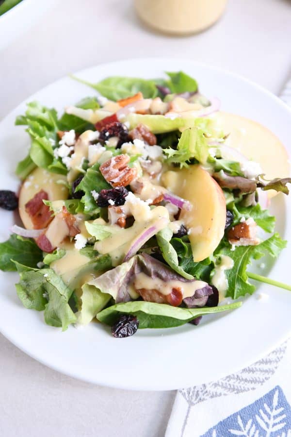 dished up portion of spinach salad on white plate with vinaigrette, bacon, onions and feta