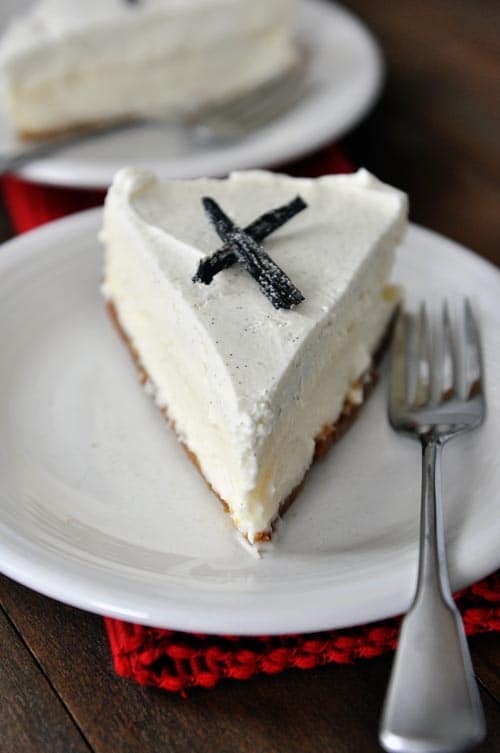 A slice of vanilla bean white chocolate cheesecake with candied vanilla beans on top.
