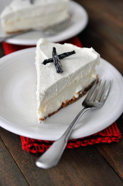 White plate with a slice of vanilla white chocolate mousse cheesecake and a fork.