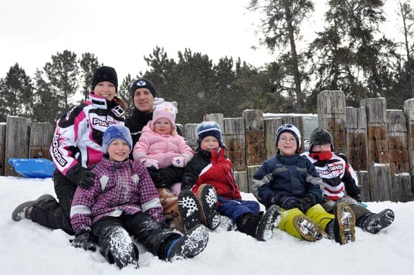 a family dressed in snow gear sitting in the snow