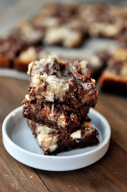 Three chocolate seven layer bars stacked on each other with the rest of the bars in the background.