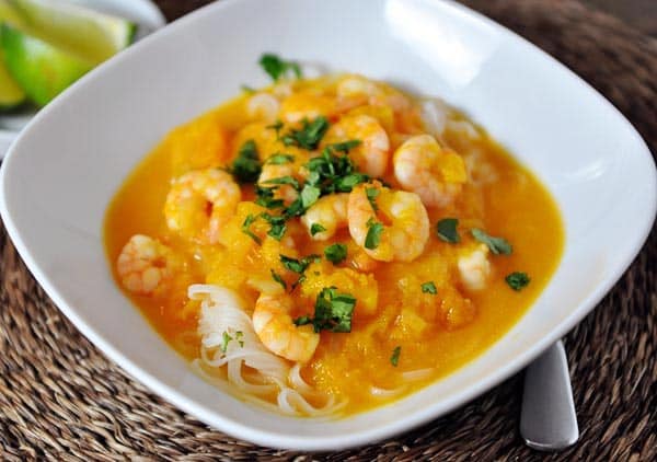 Shrimp curry sauce over rice noodles in a white bowl.