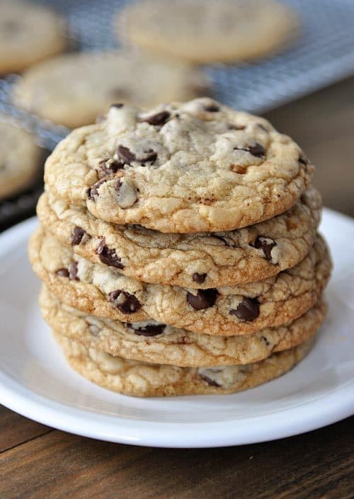 Stacked chocolate chip cookies on a white plate.