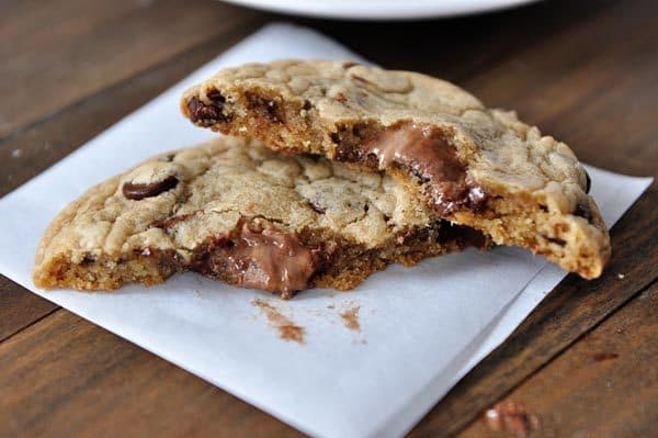 A Nutella filled chocolate chip cookie split open on a piece of parchment paper.