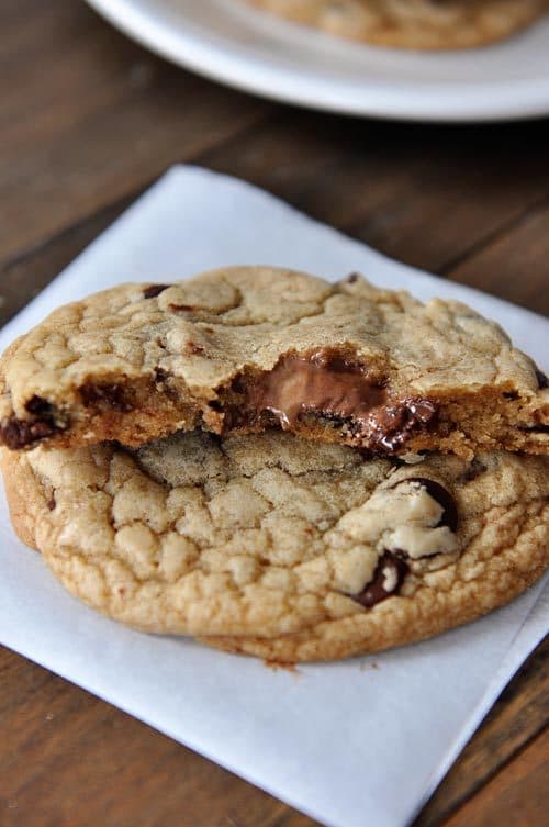 Two Nutella and peanut butter stuffed chocolate chip cookies with one split in half on top.