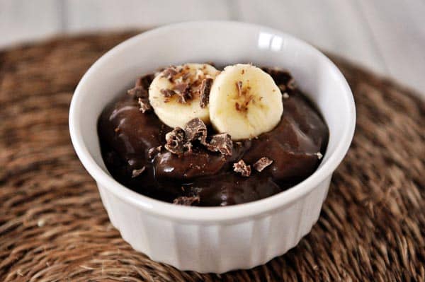 white ramekin with chocolate pudding topped with banana slices and chopped chocolate