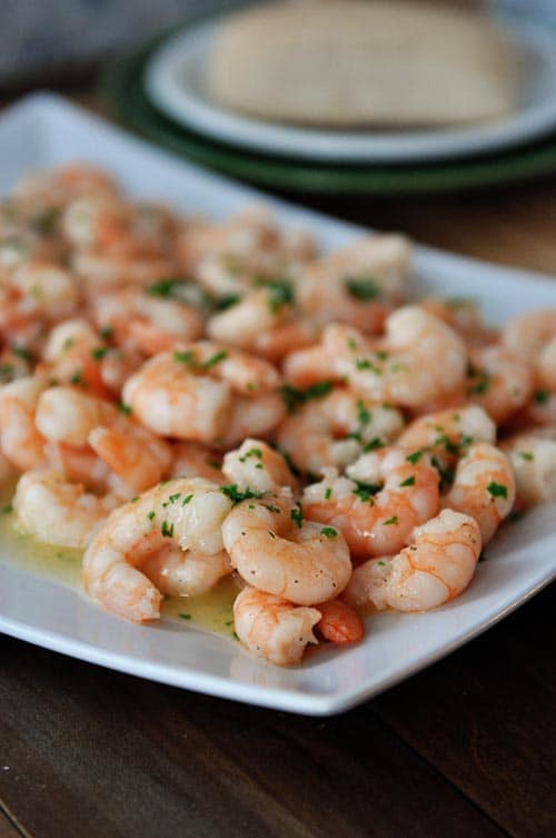 A white platter full of cooked shrimp scampi.