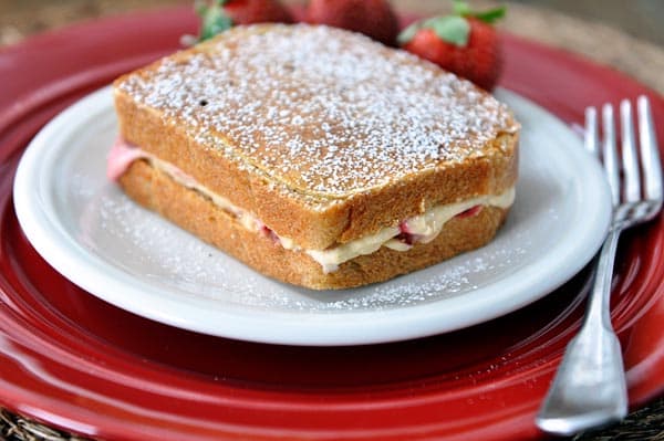 A stuffed french toast sprinkled with powdered sugar on a white plate.