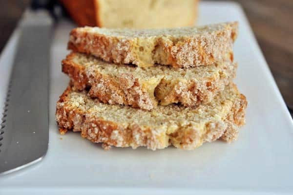 Three slices of streusel-topped banana bread stacked on top of each other on a white platter.