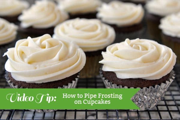 chocolate cupcakes with white piped frosting on a cooling rack