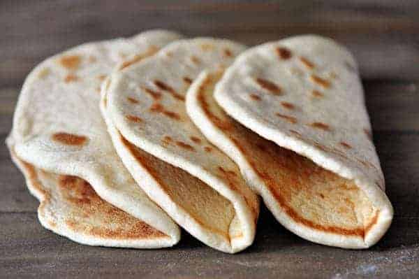 Three homemade flatbreads folded and lined up next to each other. 