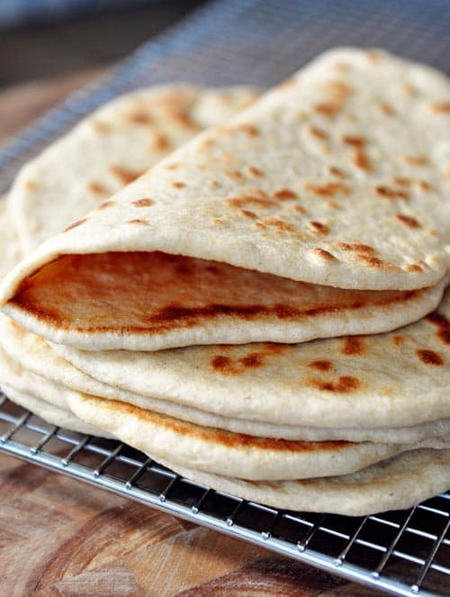 A stack of homemade flatbread cooling on a cooling rack. 