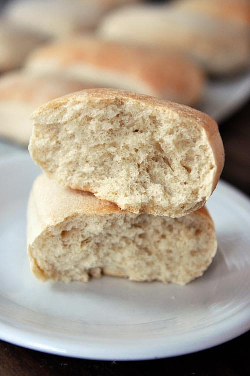 A cooked italian roll split in half and stacked on top of each other on a white plate.