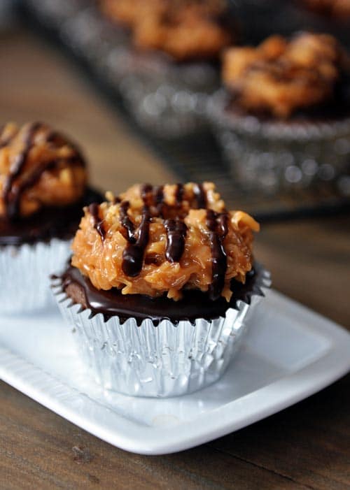 Tinfoil lined cupcakes with coconut samoa topping, chocolate ganache, and drizzled chocolate.