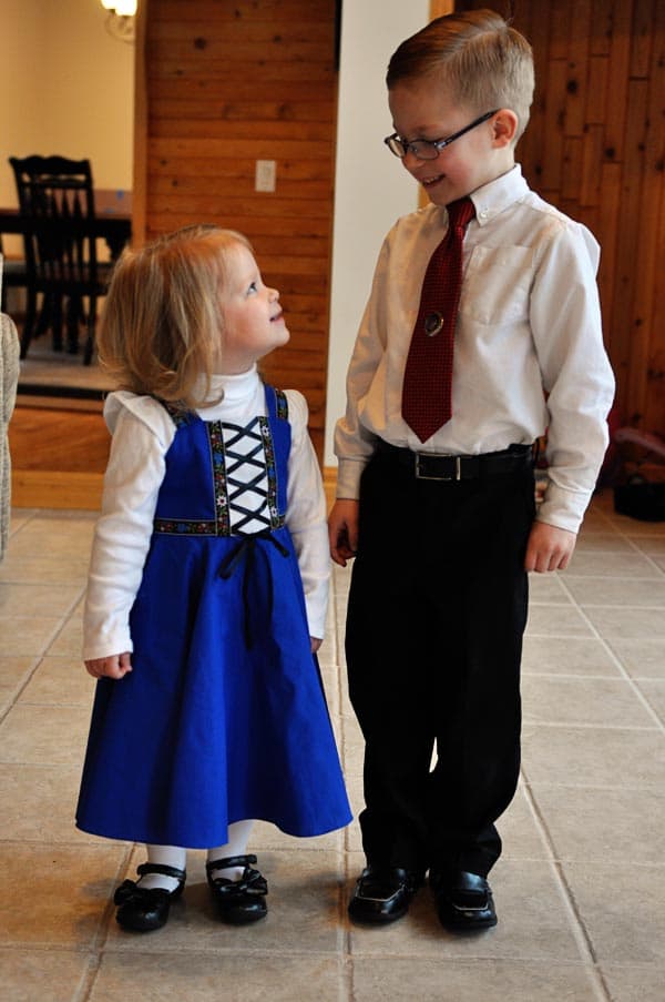 a little boys and girl in church clothes standing and looking at each other