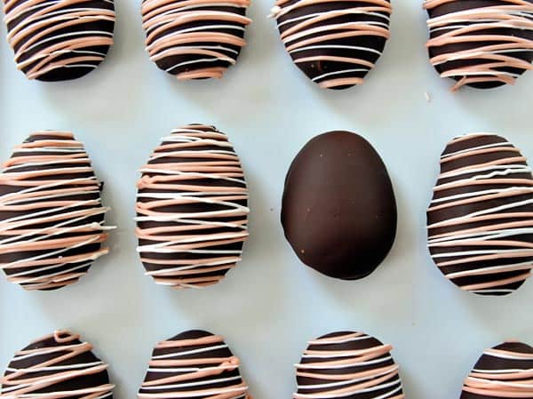 Top view of pink and white drizzled chocolate covered marshmallow eggs on a piece of parchment paper