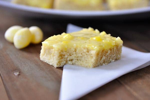 A lemon drop sugar cookie bar with a bite taken out and lemon drops beside it.