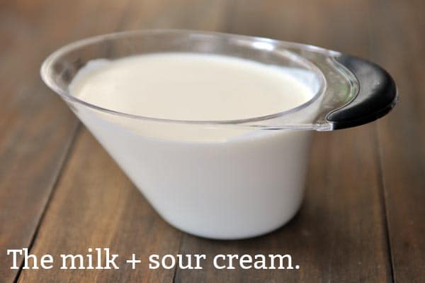 A liquid measuring cup full of milk and sour cream mixed together.