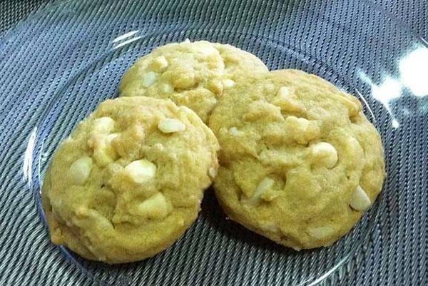 three white chocolate chip cookies on a clear plate