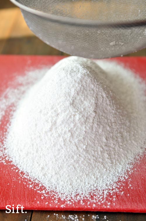 A pile of sifted flour on a red cutting board. 