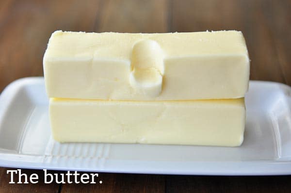 Two sticks of softened butter on a white butter plate. 