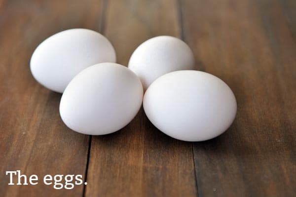 Four eggs laying on a wooden surface. 