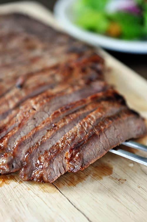 A grilled steak sliced into strips on a cutting board. 