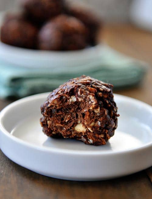 A small white plate with a half-eaten dark chocolate granola bite.