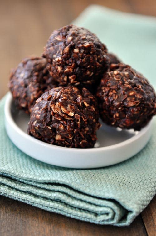 A small white plate with a bunch of dark chocolate oat granola bites.
