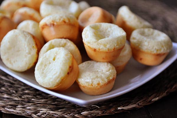 A white platter full of mini Brazilian cheese breads.