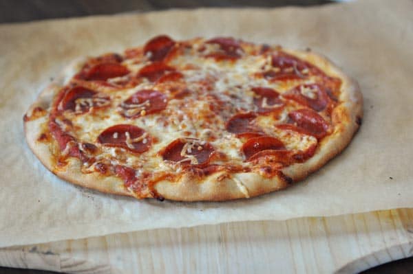 A cooked pepperoni pizza on a piece of parchment paper. 