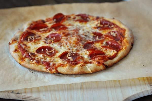 Homemade, baked pepperoni pizza on a pice of parchment paper. 