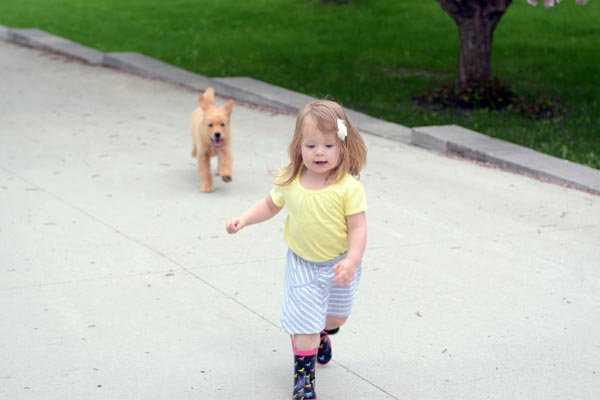 a little girl running in front of a puppy