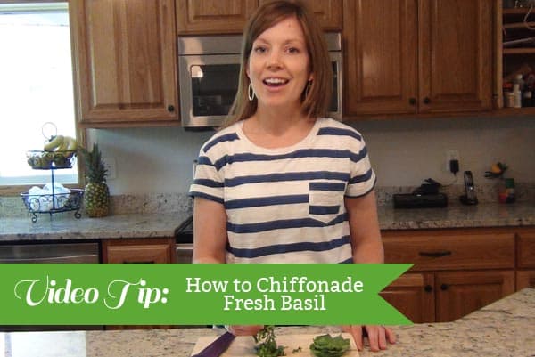 A woman standing in a kitchen with the text: How to Chiffonade Basil on the picture. 