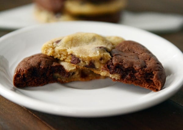 A plate with a half brownie, half chocolate chip cookie cookie split in half.