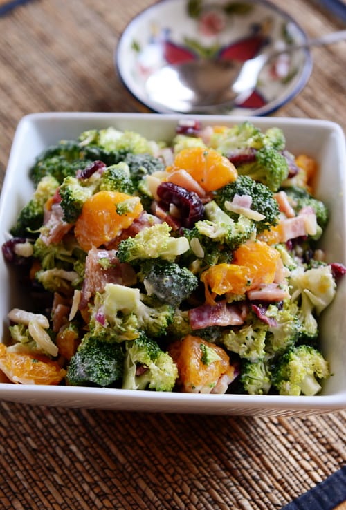 Top view of a square white dish full of mandarin broccoli and bacon salad.