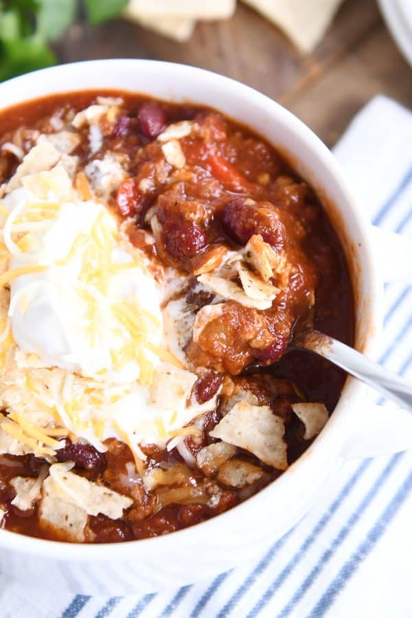 Top down view of classic slow cooker chili in white bowl with cheese and sour cream.