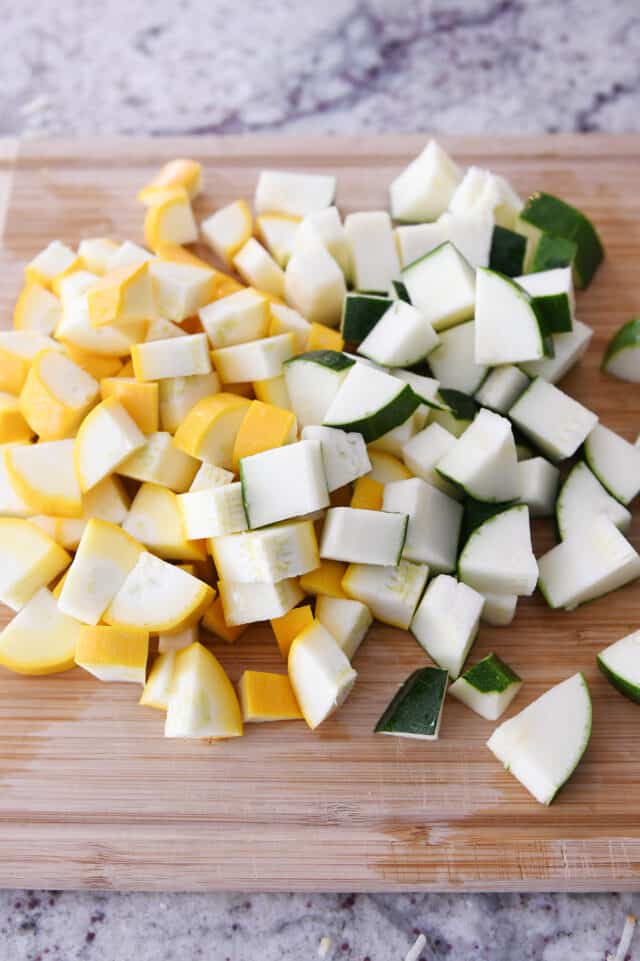 Cutting board with chopped zucchini and yellow squash.